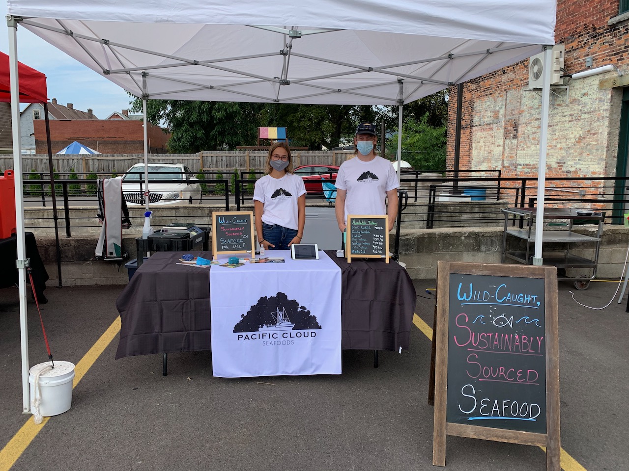 Pacific Cloud Seafoods farmers market table with cooler bags and signage