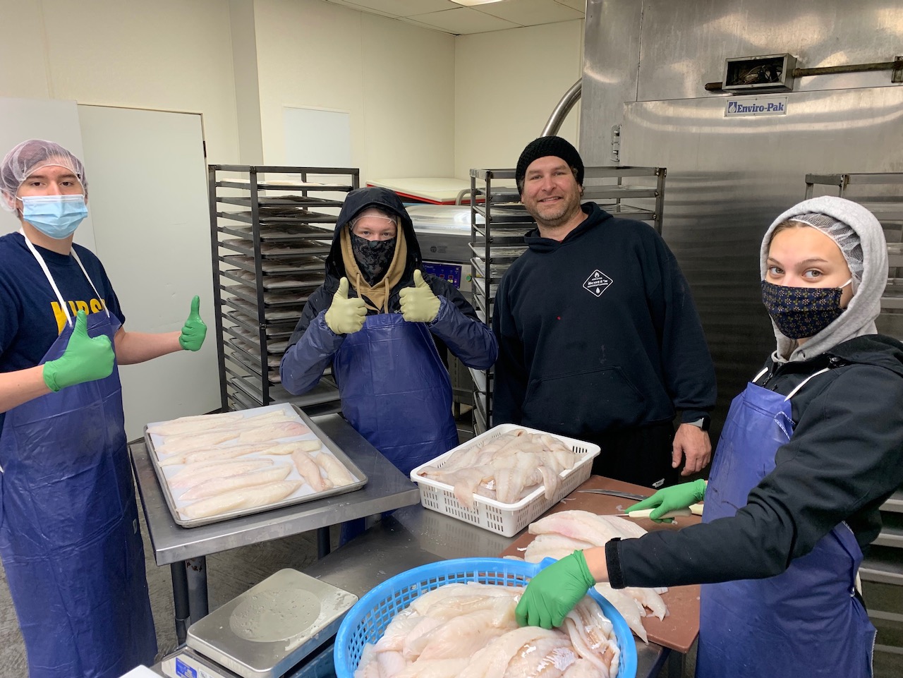 Seafood crew holding trays of packaged fish